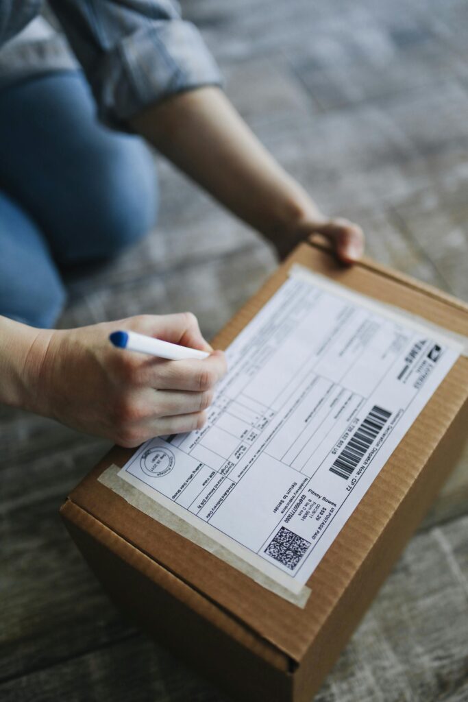 Close-up view of hands writing on a shipping box indoors.